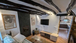 A cozy living room with a sofa, a TV, and a fireplace. - Townhouse with large terrace and mountain views in Málaga village (Villanueva del Rosario)