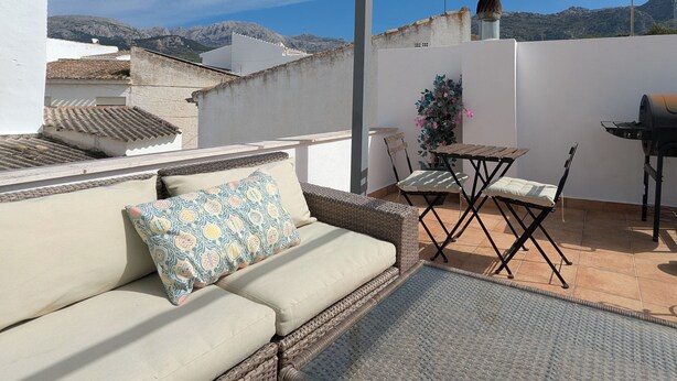A rooftop terrace with a sofa, a table, and chairs. - Townhouse with large terrace and mountain views in Málaga village (Villanueva del Rosario)