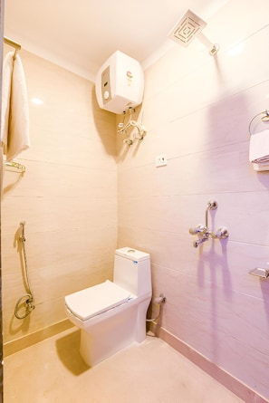 A bathroom with a toilet, a shower, and a towel rack. - Taksh Grand Stays (New Delhi)
