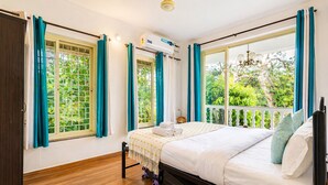 A bedroom with a bed, air conditioning unit, and windows with curtains.