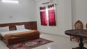 A bedroom with a bed, a round table, and three chairs. - Hotel & Bothgaya Waterpark  (Gaya)