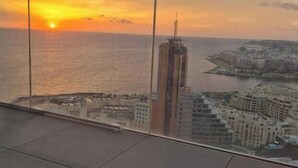 Een hoog gebouw met uitzicht op de zonsondergang boven de zee.