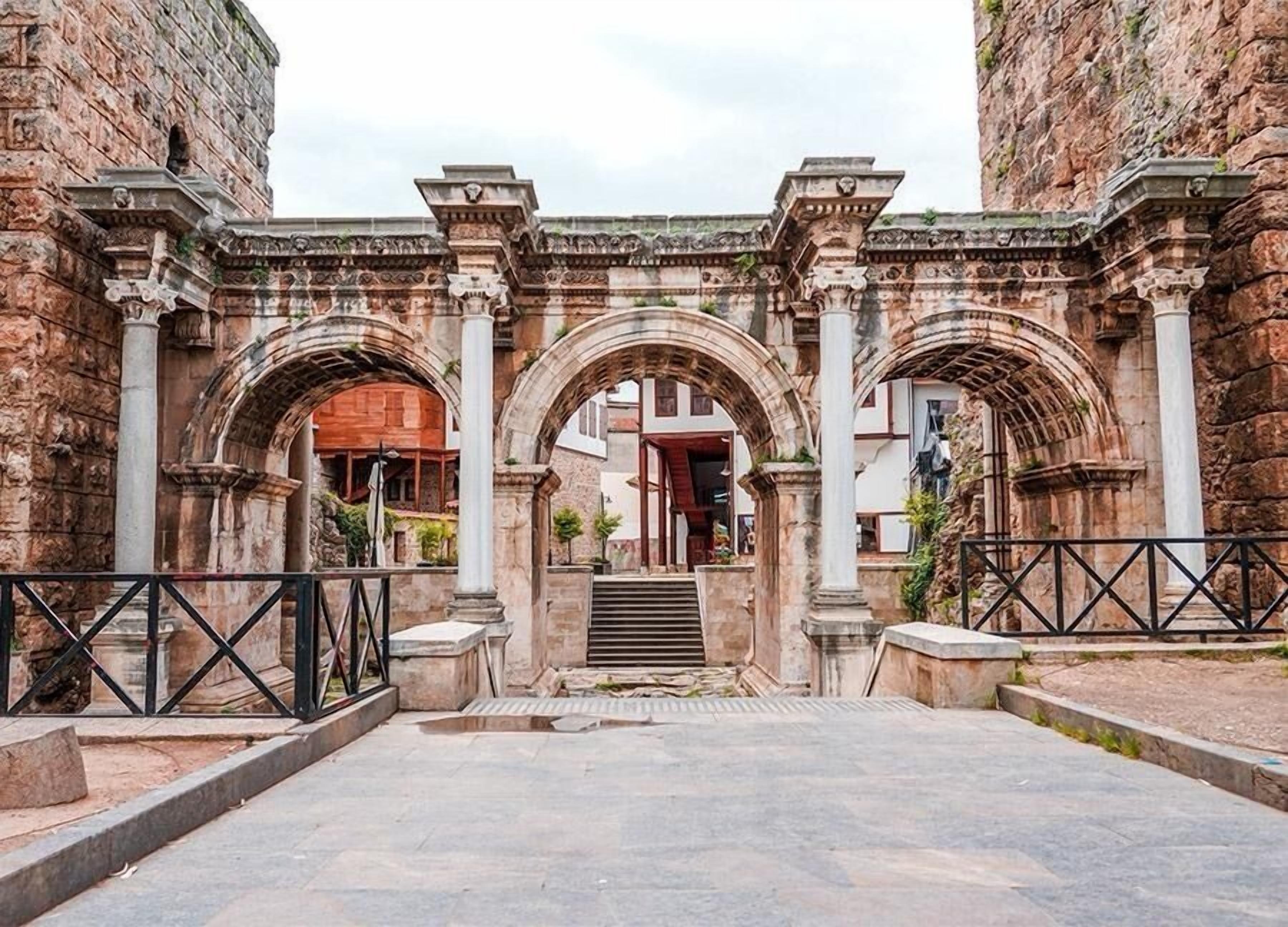 An entrance with three arches, a staircase, and stone walls.