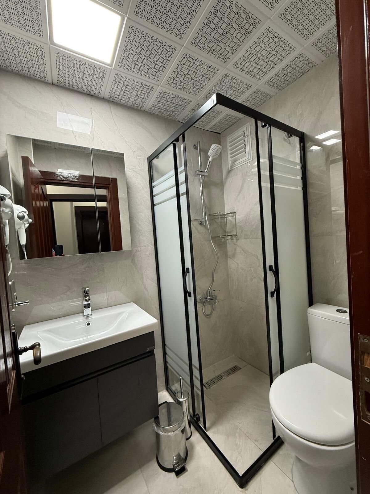 A bathroom with a glass-enclosed shower, a sink with a mirror, and a toilet.