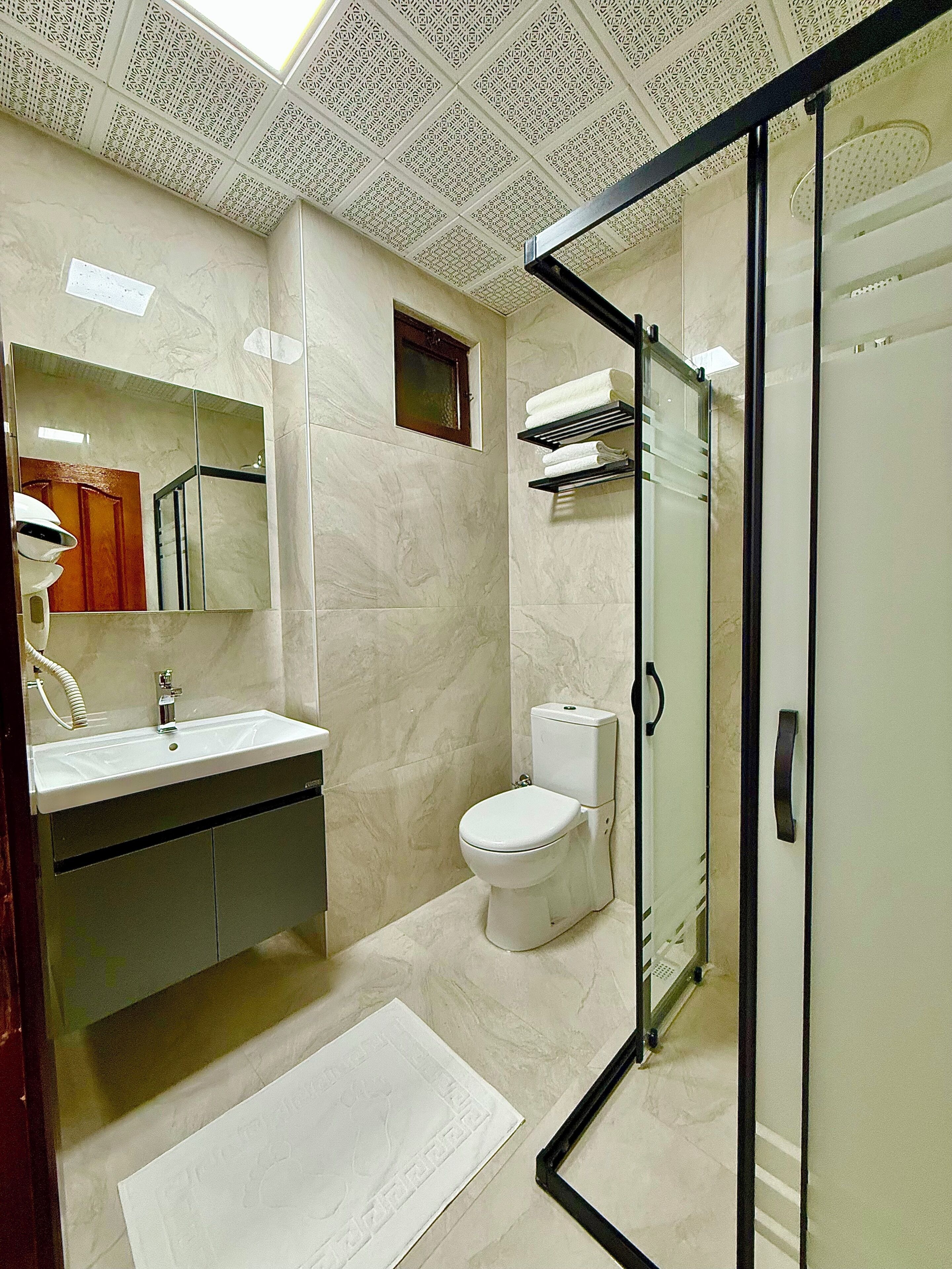 Une salle de bain équipée d’un lavabo, d’un miroir, de toilettes et d’un espace douche.