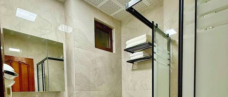 A bathroom with a sink, mirror, toilet, and shower area.