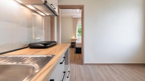 A modern kitchen with a stainless steel sink, wooden countertop, and a built-in oven. - KYMA STAY - Beachfront apartments  (Thermaikos)
