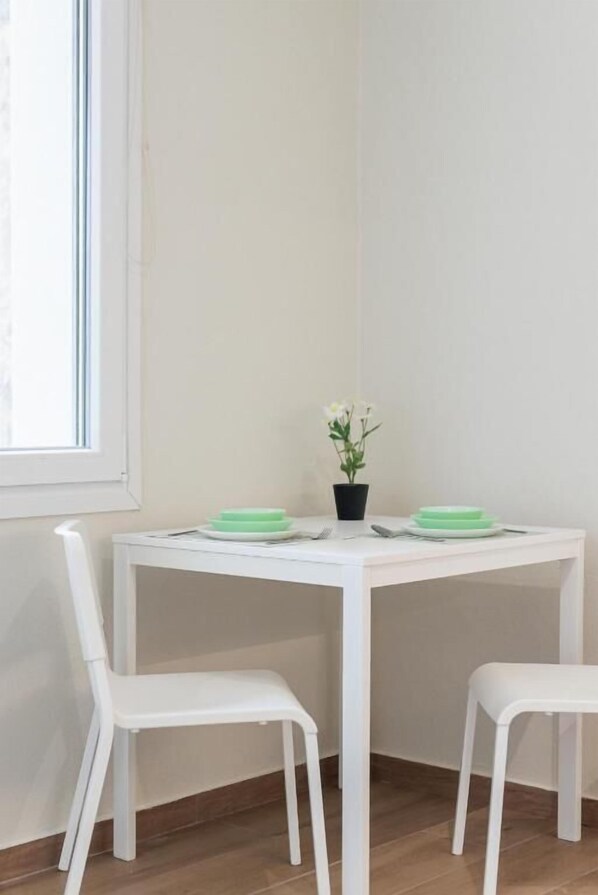 A white table with two chairs, a potted plant, and green plates. - KYMA STAY - Beachfront apartments (Thermaikos)