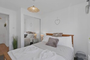 A bedroom with a bed, a bedside table, a mirror, a hanging light fixture, and a heart-shaped decoration on the wall. - Saughton 2BR | Free Private Parking | Near Tram (Edinburgh)