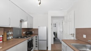 Una cocina moderna con armarios blancos, un lavamanos de acero inoxidable y un horno empotrado.