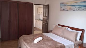 Een slaapkamer met een bed, nachtkastje, kast en schilderij aan de muur.