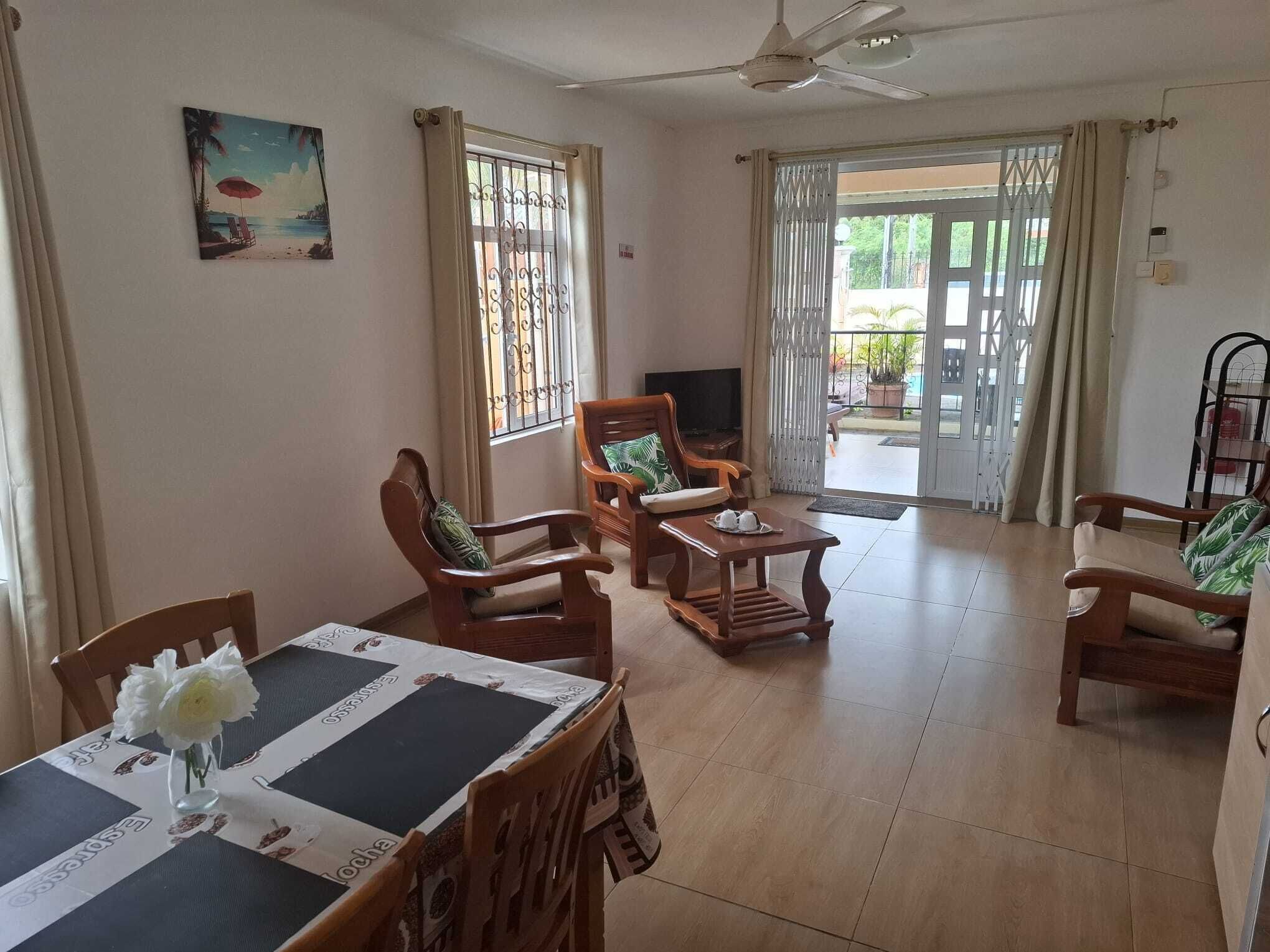 A spacious living area with a dining table, chairs, a sofa, and a television.