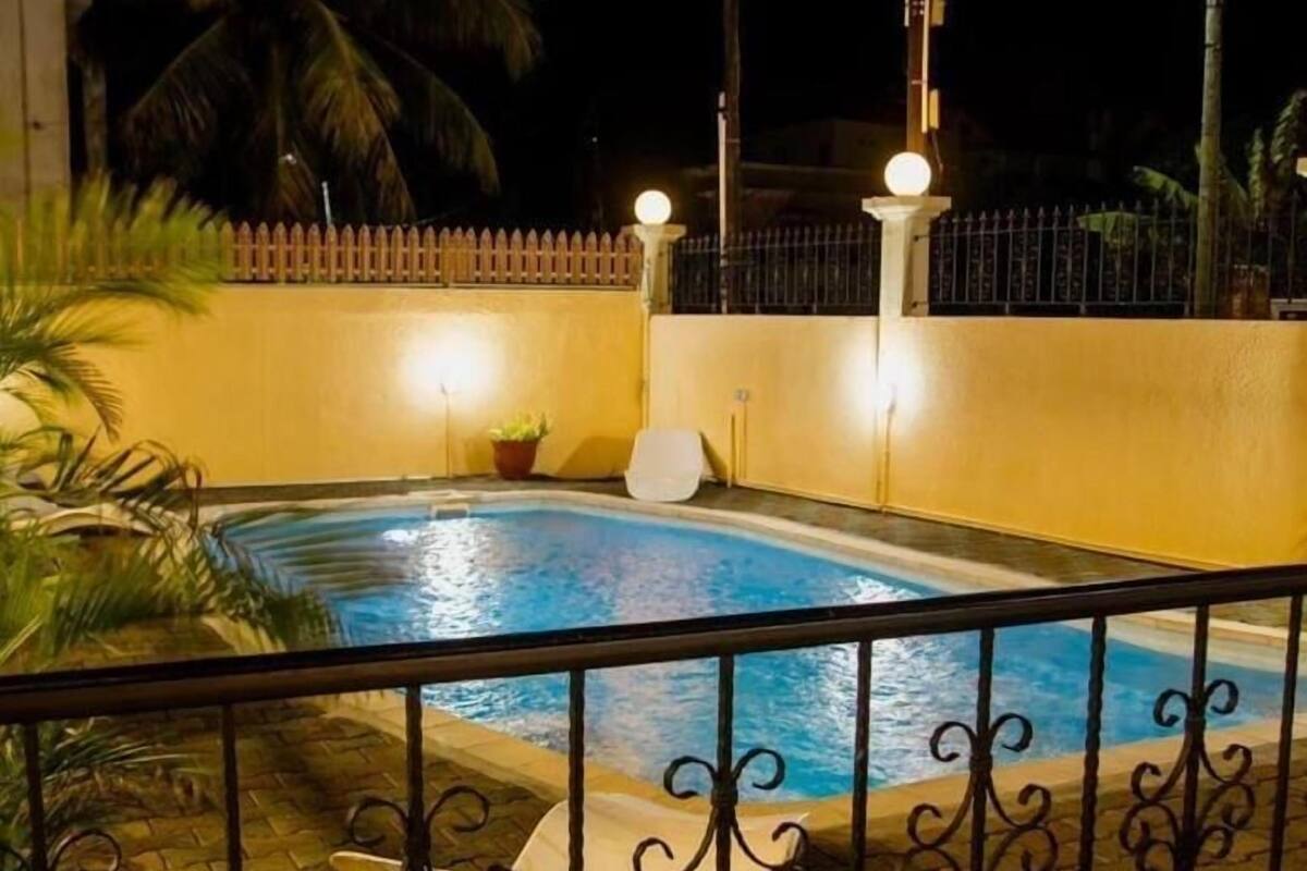 Une piscine entourée d’une clôture en métal et agrémentée d’un lampadaire.