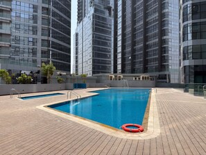 A rooftop swimming pool with a lifebuoy, surrounded by modern high-rise buildings. - Silkhaus Vacation Homes Elegant 2BR With Maid Room in Radiant Heights (Abu Dhabi)