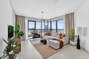 A modern living room with a sofa, coffee table, and potted plants. - Silkhaus Vacation Homes Elegant 2BR With Maid Room in Radiant Heights (Abu Dhabi)