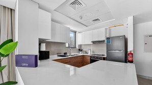 Une cuisine moderne dotée d’un îlot central, d’appareils électroménagers en acier inoxydable et d’un extincteur.