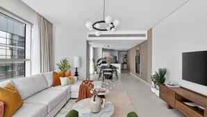 Un salon moderne avec un canapé, une table basse et un téléviseur. Il y a également un coin repas avec une table et des chaises.