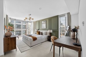 A modern hotel room with a large bed, a desk, a chair, a lamp, and a view of the city. - Silkhaus Vacation Homes Elegant 2BR With Maid Room in Radiant Heights (Abu Dhabi)