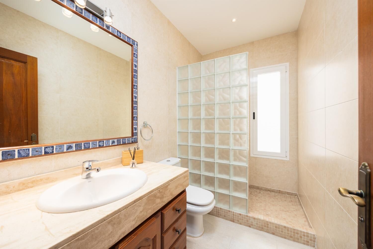 A bathroom with a large mirror, a sink, a toilet, and a glass shower enclosure.