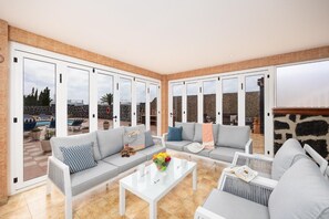 A spacious patio with two sofas, a coffee table, and a view of a swimming pool and stone wall. - Villa Marisol with air con and private heated pool (Playa Blanca)