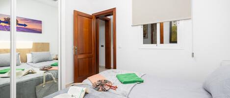 A bedroom with a bed, a wardrobe, a window with a blind, and a painting on the wall.