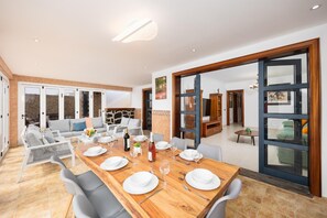 A dining area with a wooden table set for four, a sofa, and a view of the outside. - Villa Marisol with air con and private heated pool (Playa Blanca)