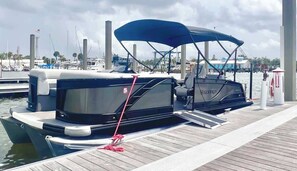 Zwei Boote liegen in einer Marina mit einem hölzernen Deck und einem überdachten Bereich festgemacht.