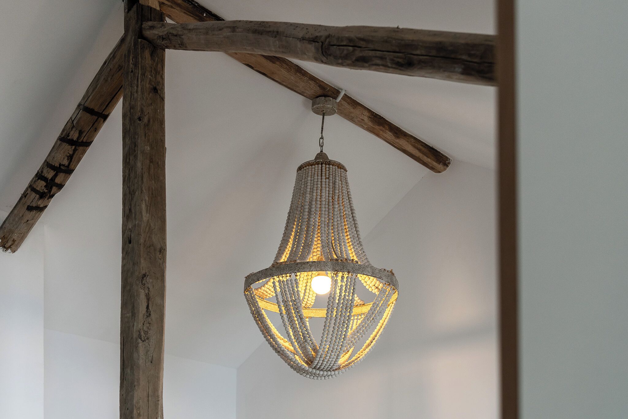 A chandelier with a geometric design hanging from a wooden beam structure.