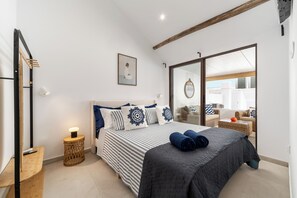 Ein Schlafzimmer mit Bett, Nachttisch, Lampe und Blick durch eine Glastür.
