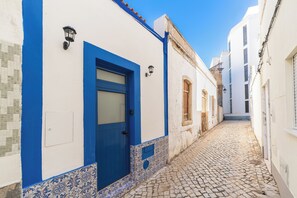 Eine enge Kopfsteinpflasterstraße, gesäumt von weißen Gebäuden mit blauen Akzenten.