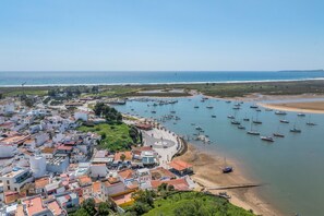 A coastal town with a marina, buildings, and a beach. - Enjoy exclusive use of two beautifully refurbished townhouses combined into one spacious 4-bedroom home in Alvor Old Town. Steps from the harbour, beach and restaurants, with sunny sea-view terraces jacuzzi, 2living rooms, 2kitchens, AC throughout. (Portimao)
