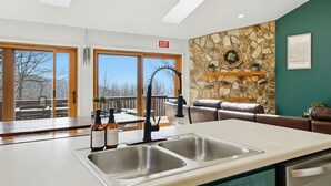 A modern kitchen with a large window, a stone accent wall, and a view of the outdoors. - Mtn Resort Getaway - 4 Bed, 3 Bath - Lake with Kayaks , Golf, Pools, Pickleball (Jasper)