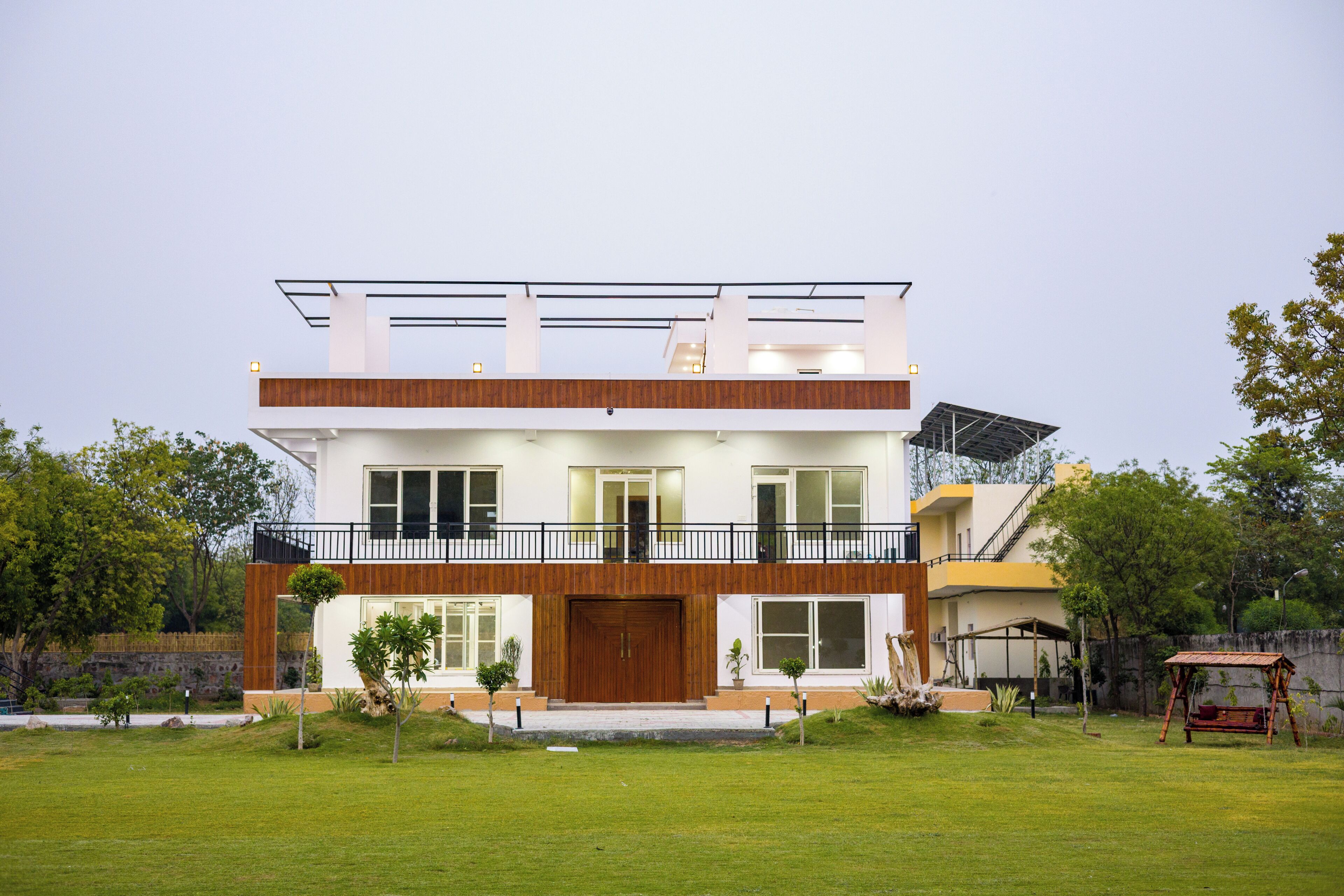 Een modern huis met twee verdiepingen, een balkon, grote ramen en een verzorgd gazon.