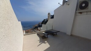 Eine Dachterrasse mit Blick auf das Meer, einer Bank und einer Satellitenschüssel.