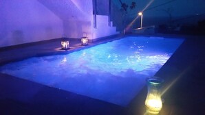 Ein Schwimmbad mit zwei beleuchteten Laternen und einer Kerze am Rand.