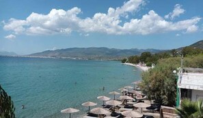 Une plage avec une eau cristalline, des parasols et une vue sur la côte.