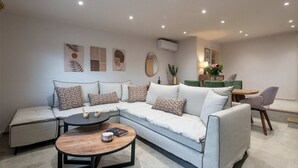 Una sala moderna con un sofá modular, una mesa de centro redonda y un comedor con una mesa y sillas.