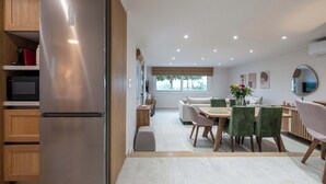 Una cocina moderna con un refrigerador de acero inoxidable, armarios de madera y un comedor con mesa y sillas.