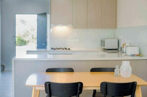 A modern kitchen with a wooden table and chairs, a microwave, and a small window. - Bright 2BDR Apt with Pool Access Williamstown (Williamstown)
