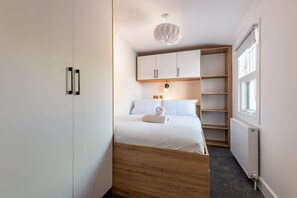 Ein Schlafzimmer mit Bett, Schrank, Heizkörper und Fenster.