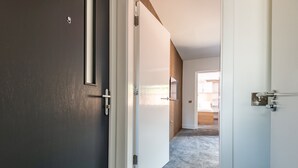 En hall med ett heltäckningsmatta på golvet, en dörr med ett handtag och en väggpanel av trä.