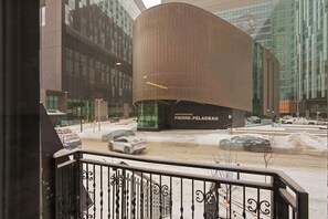 Ein modernes Gebäude mit einer gewölbten Fassade, einer Beschilderung mit der Aufschrift 'AMPHITHEATRE PIERRE-PÉLADEAU' und einer verschneiten Straße mit Autos.