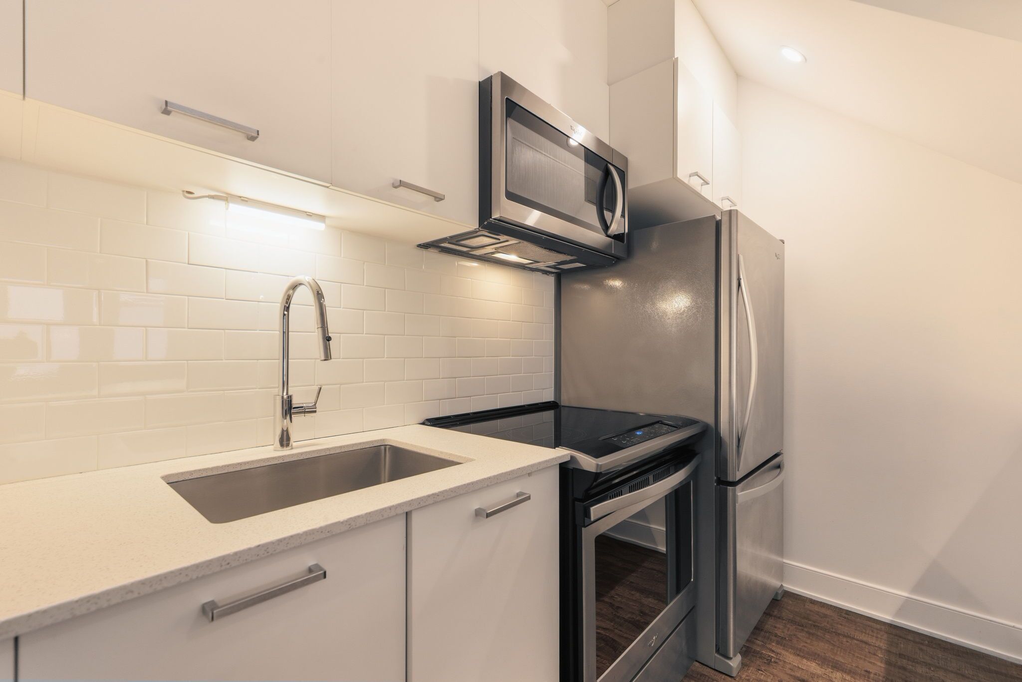 A modern kitchen with a stainless steel refrigerator, a built-in microwave, and a double oven.