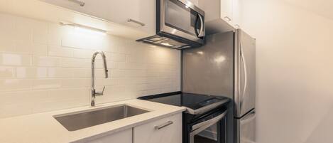 A modern kitchen with a stainless steel refrigerator, a built-in microwave, and a double oven.