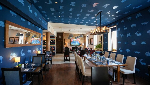 Un restaurant dont le plafond est décoré de motifs animaliers, avec des tables et des chaises en bois.
