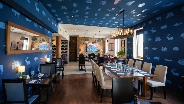 Un restaurant dont le plafond est décoré de motifs animaliers, avec des tables et des chaises en bois.
