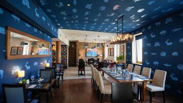 Un restaurante con techo decorado con estampados de animales, mesas y sillas de madera.