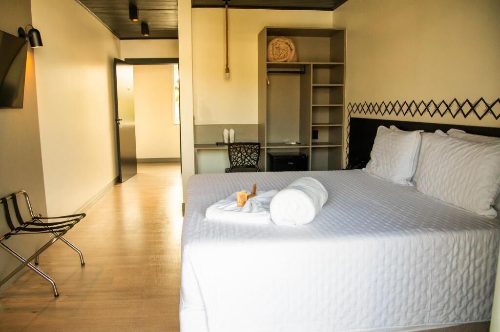 A hotel room with a bed, a chair, a wardrobe, and a desk.