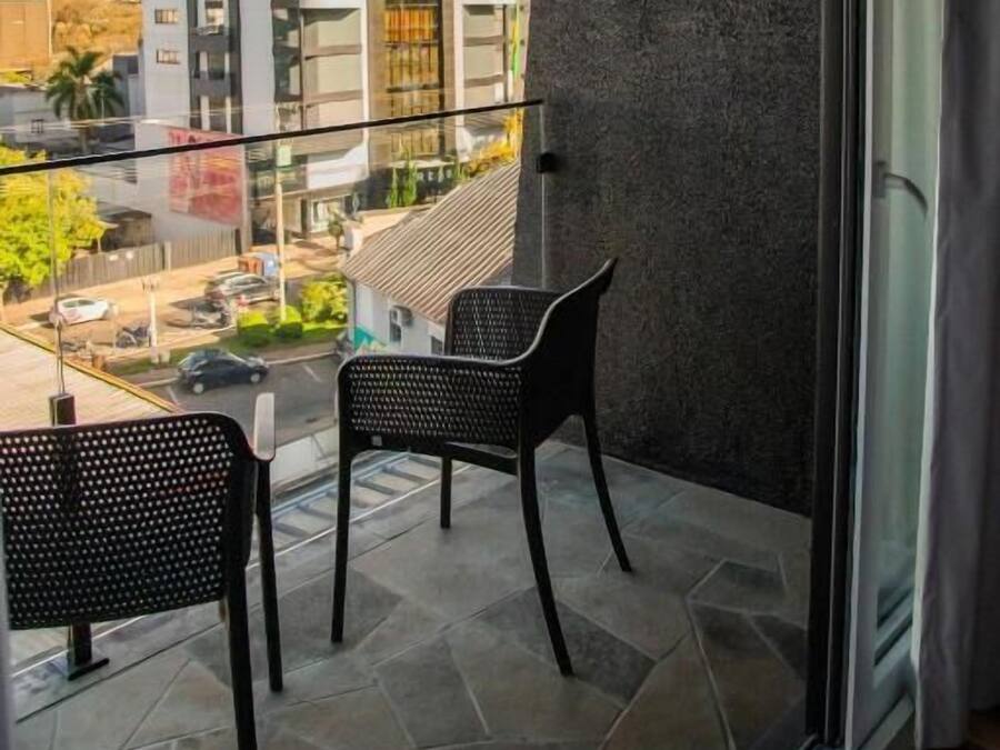 Ein Balkon mit zwei Stühlen, einem Glastisch und Blick auf ein modernes Gebäude.