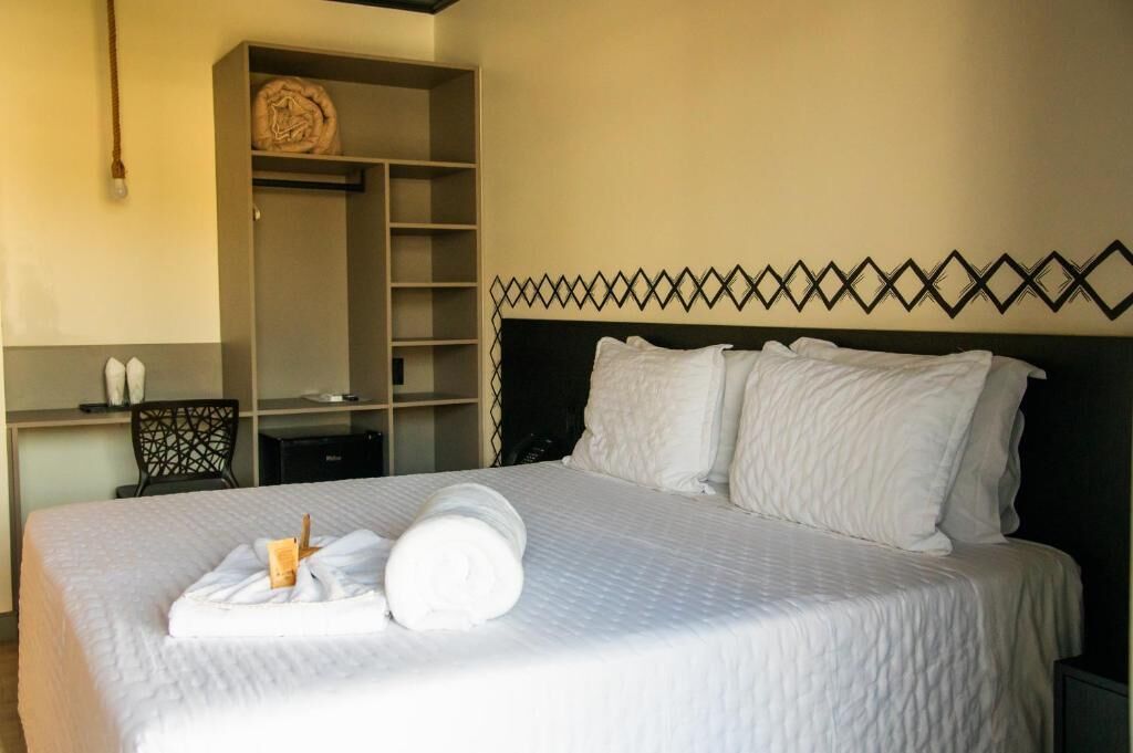 A neatly made bed with white linens, a headboard with a geometric pattern, and a wardrobe with a circular mirror.
